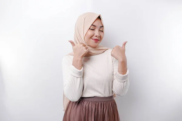スカーフを被った興奮したアジア系イスラム教徒の女性は 白い背景によって隔離された承認の手のジェスチャーを親指アップします — ストック写真