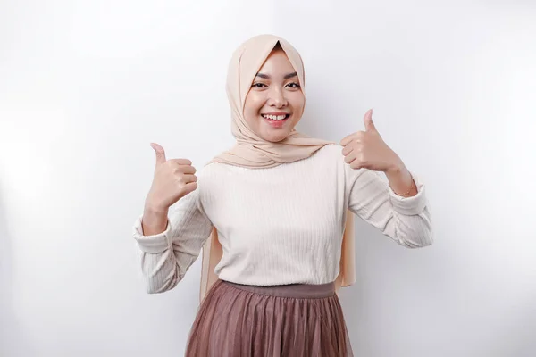 スカーフを被った興奮したアジア系イスラム教徒の女性は 白い背景によって隔離された承認の手のジェスチャーを親指アップします — ストック写真