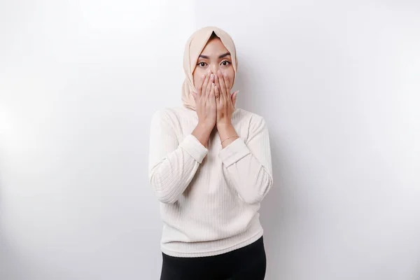 スカーフを被った若いアジア系イスラム教徒の女性の肖像画は 静かにされ 深刻な顔で急いで 唇に押された指で急いで 白い背景によって隔離されています — ストック写真