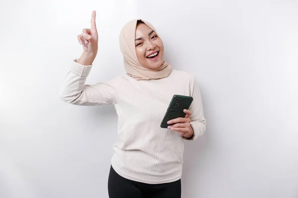 Podekscytowana Azjatka Hidżabie Wskazująca Miejsce Ksero Trzymając Telefon Odizolowana Białym — Zdjęcie stockowe
