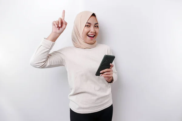Возбужденная Азиатка Носящая Хиджаб Указывая Копировальное Пространство Сверху Держа Телефон — стоковое фото