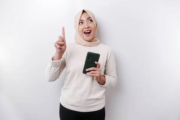 Podekscytowana Azjatka Hidżabie Wskazująca Miejsce Ksero Trzymając Telefon Odizolowana Białym — Zdjęcie stockowe