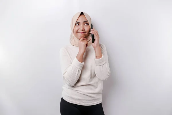 一位有思想的年轻的亚洲穆斯林妇女 头戴头巾 下巴紧闭 一边打电话 一边与白人背景隔离 — 图库照片