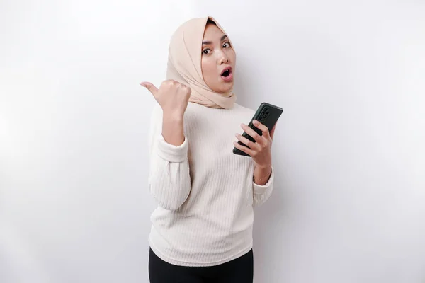 Zszokowana Azjatycka Muzułmanka Hidżabie Wskazująca Miejsce Przy Telefonie Odizolowana Białym — Zdjęcie stockowe