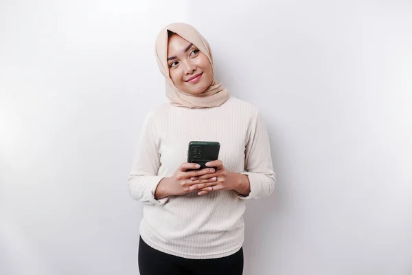 白い背景によって隔離された彼女の携帯電話を保持し スカーフを身に着けている幸せなアジアのイスラム教徒の女性 — ストック写真
