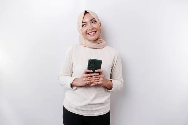 白い背景によって隔離された彼女の携帯電話を保持し スカーフを身に着けている幸せなアジアのイスラム教徒の女性 — ストック写真
