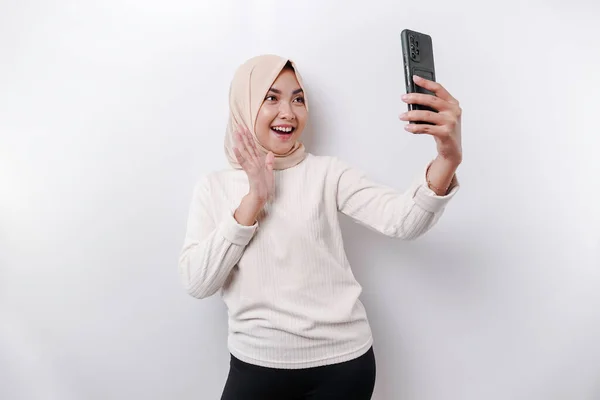 Szczęśliwa Azjatycka Muzułmanka Nosząca Chustę Głowie Trzymająca Telefon Odizolowana Przez — Zdjęcie stockowe