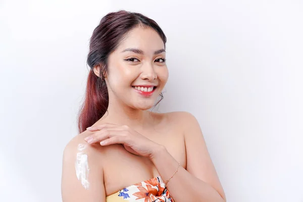 stock image Skin Care Products Concept. Asian woman applying moisturizing lotion on body after shower, standing wrapped in towel, cropped image