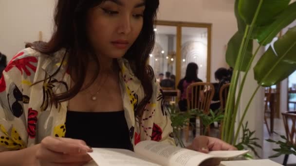 Restoranda Oturmuş Kitap Okuyan Sevimli Bir Asyalı Kadın — Stok video