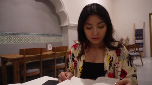 Restoranda Oturmuş Kitap Okuyan Sevimli Bir Asyalı Kadın — Stok video