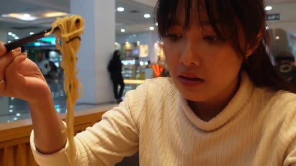 매력적인 아시아 여자는 레스토랑에서 식사를하고있다 젓가락을 사용하여 국수를 — 비디오