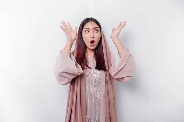 stock image Shocked Asian Muslim woman wearing a headscarf pointing at the copy space on top of her, isolated by a white background