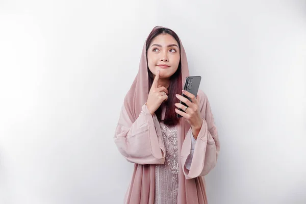 Задумчивая Молодая Азиатская Мусульманка Хиджабе Держа Подбородок Разговаривая Телефону Изолированному — стоковое фото