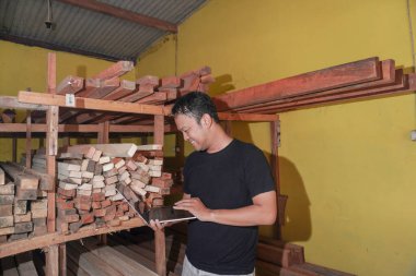 Yakışıklı Asyalı adam marangozluk atölyesine bakarken gülümsüyor.