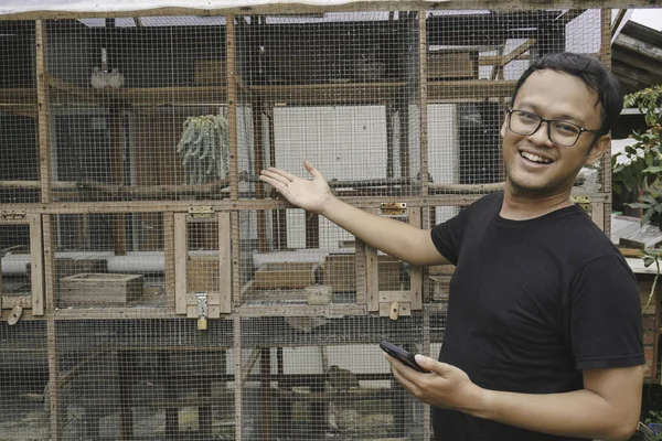 stock image Handsome Asian man is smiling and standing in front of bird cage