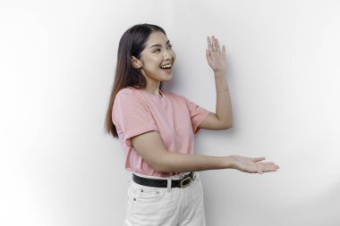 Heyecanlı Asyalı kadın pembe tişört giyiyor, yanındaki fotokopi odasını gösteriyor, beyaz arka planla izole edilmiş.