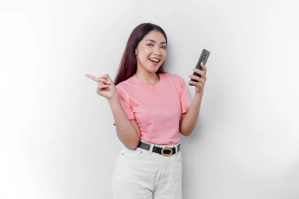 Portret Szczęśliwej Azjatki Ubranej Różowy Shirt Trzymającej Telefon Wskazującej Obok — Zdjęcie stockowe