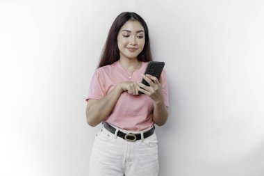 Mutlu bir Asyalı kadının portresi pembe tişört giyiyor ve beyaz arka planla izole edilmiş telefonunu tutuyor.