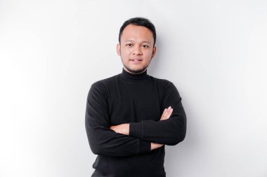 An Asian young confident man posing with crossed arm against a white background.
