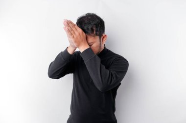 Siyah gömlekli dindar bir Asyalı beyaz bir geçmişle Tanrı 'ya dua ediyor.