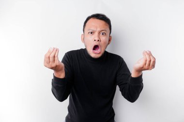 The angry and mad face of Asian man in black shirt isolated white background.