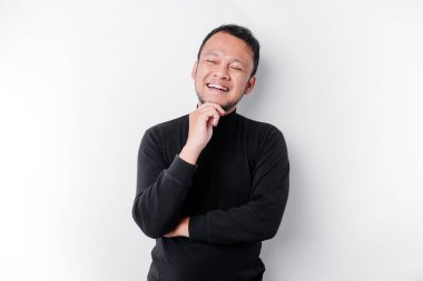 Siyah gömlekli düşünceli genç bir adam, beyaz arka planla izole edilmiş, bir kenara bakıyor.