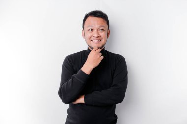 Siyah gömlekli düşünceli genç bir adam, beyaz arka planla izole edilmiş, bir kenara bakıyor.