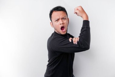 Siyah gömlek giyen heyecanlı Asyalı adam gururla gülümseyerek kollarını ve kaslarını kaldırarak güçlü bir hareket sergiliyor.