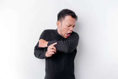 Siyah tişörtlü genç Asyalı adam izole edilmiş beyaz arka plan üzerinde duruyor vücut kokusu, kokuşmuş ve iğrenç, dayanılmaz bir koku. Kötü koku konsepti.