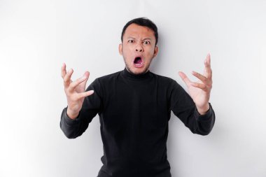 The angry and mad face of Asian man in black shirt isolated white background.