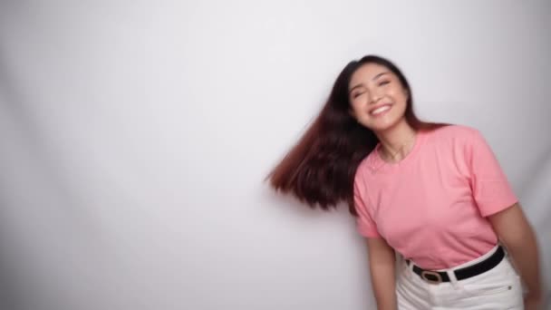 笑着的年轻亚洲女人穿着粉红的衬衫 在有白色背景的工作室里给传统的问候打了个手势 — 图库视频影像