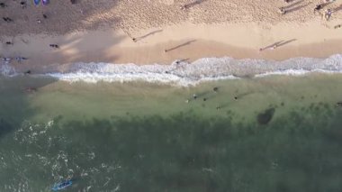 İnsanlar Gunung Kidul, Endonezya 'daki güzel plajlarda gün ışığında mercan kayaları, yeşil deniz yosunları ve ön planda alçak gelgitlerle oynuyorlar.