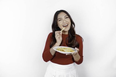 Beyaz arka planda izole edilmiş patates kızartması yiyen gülümseyen Asyalı genç kız görüntüsü