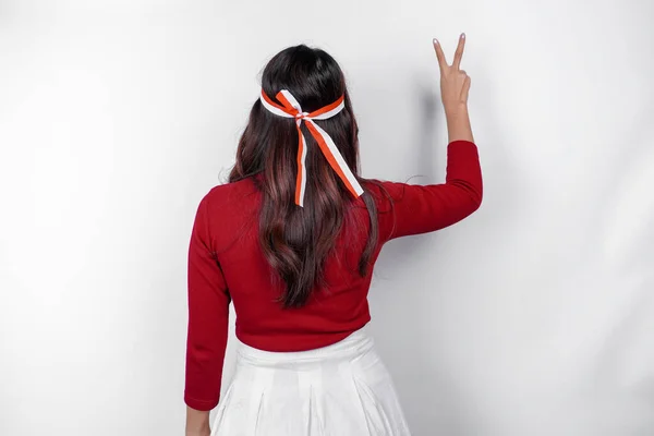 stock image Back view of a young Asian woman wearing a red top expressing peace sign by fingers