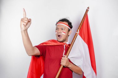 Aydınlanmış genç bir Asyalı adam kırmızı tişört giyiyor ve elinde Endonezya 'nın bayrağı var. Beyaz arka plandaki fikirlerden esinlenmiş gibi görünüyor.