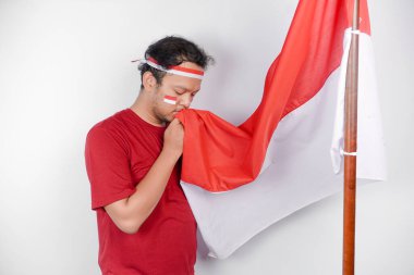 Endonezyalı adam Endonezya bayrağını tutarken gururla selam veriyor. Endonezya 'nın bağımsızlık günü konsepti.