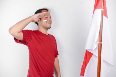 Endonezyalı adam Endonezya bayrağını tutarken gururla selam veriyor. Endonezya 'nın bağımsızlık günü konsepti.