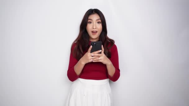 Портрет Щасливої Азіатки Червоній Сорочці Тримаючи Телефон Ізольований Білим Тлом — стокове відео