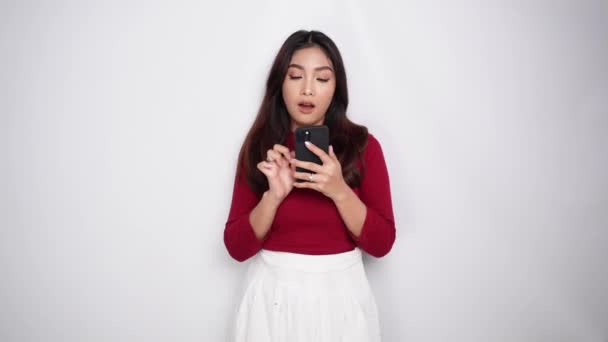 Удумлива Молода Азіатка Носить Червону Футболку Тримає Свій Телефон Надихаючись — стокове відео