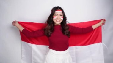 Endonezya Bağımsızlık Günü 'nü kutlamak için elinde Endonezya bayrağını tutan mutlu Endonezyalı kadın beyaz arka planda izole edilmiş..