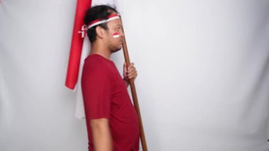Endonezyalı adam Endonezya bayrağını tutarken gururla selam veriyor. Endonezya 'nın bağımsızlık günü konsepti.