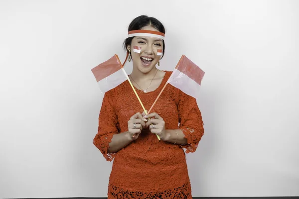 インドネシアの赤いケバヤを着て インドネシアの旗を掲げて白い背景で孤立したインドネシアの独立記念日を祝うインドネシアの女性の笑顔 — ストック写真