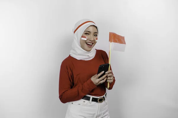 Uśmiechnięta Azjatycka Muzułmanka Czerwonej Bluzce Białym Hidżabie Trzymająca Telefon Flagę — Zdjęcie stockowe