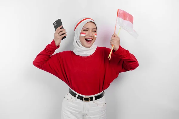 Uśmiechnięta Azjatycka Muzułmanka Czerwonej Bluzce Białym Hidżabie Trzymająca Telefon Flagę — Zdjęcie stockowe