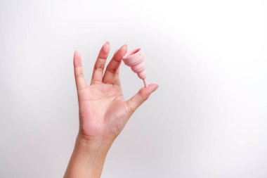 Beyaz arka planda regl bardağını tutan kadının yakın plan fotoğrafı. Kadın sağlığı konsepti, sıfır atık alternatif
