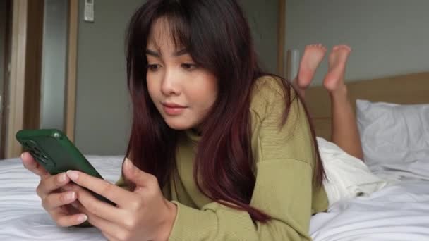 아시아의한 여성은 침대에 스마트폰을 감정을 느끼고 — 비디오