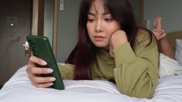 아시아의한 여성은 침대에 스마트폰을 감정을 느끼고 — 비디오