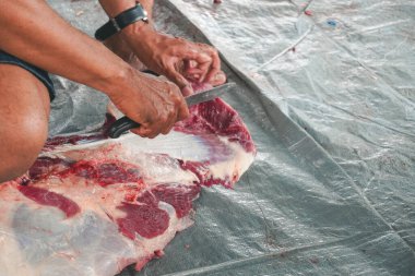 A portrait of Muslims cutting meat on Eid Al Adha by using cutting knife