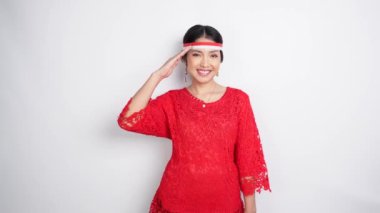 Kırmızı kebaya ve bayrak bandı takan güzel Asyalı kadın 17 Ağustos 'ta Endonezya' nın bağımsızlık gününü beyaz arka planda kutluyor.