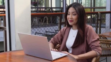 Uzaktan kumandalı bir kafede çalışan güzel bir Asyalı kadın bilgisayarını kullanıyor. Çalışanlar online video görüşmesi yapıyor.